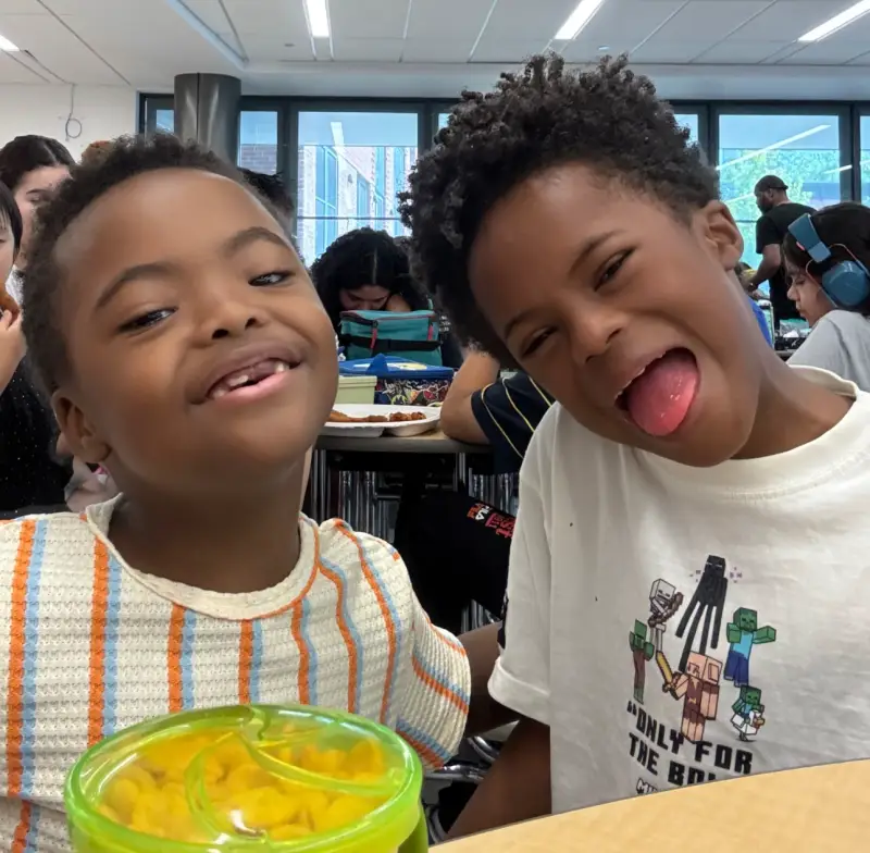 Noah laughing beside another child at a school lunch table